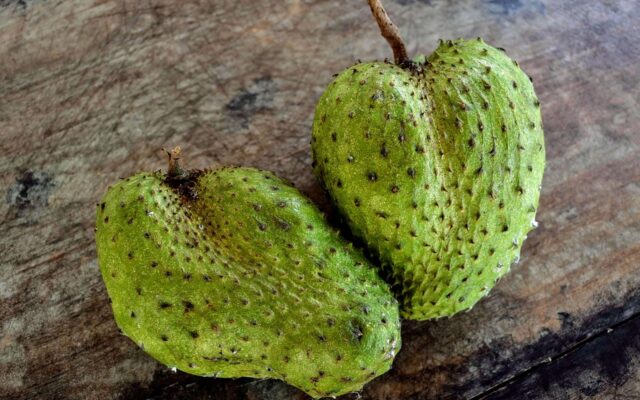 Fruta de guanábana entera y partida con su pulpa blanca