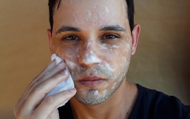 Persona lavándose la cara con agua en el lavamanos
