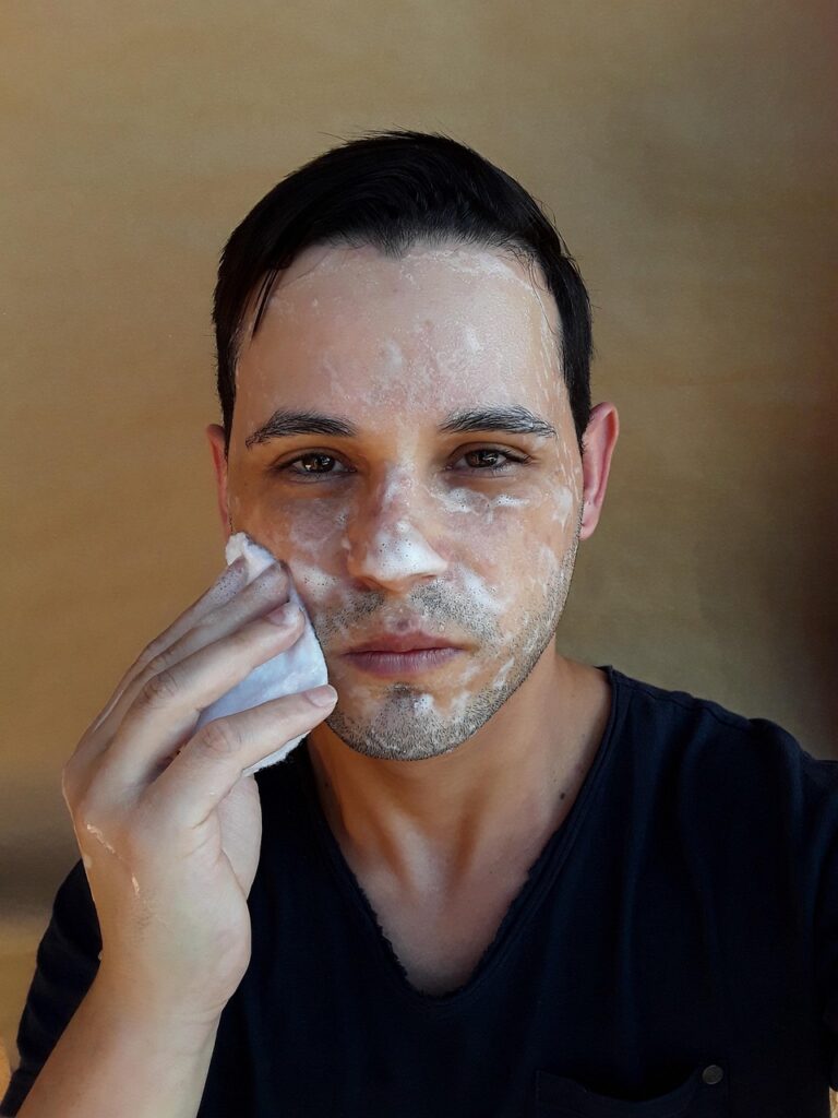 Persona lavándose la cara con agua en el lavamanos